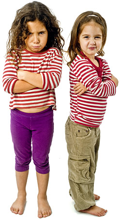 Zwei Kinder mit mürrischen Gesichtsausdrücken, die ein gestreiftes Oberteil tragen und die Arme verschränkt haben.